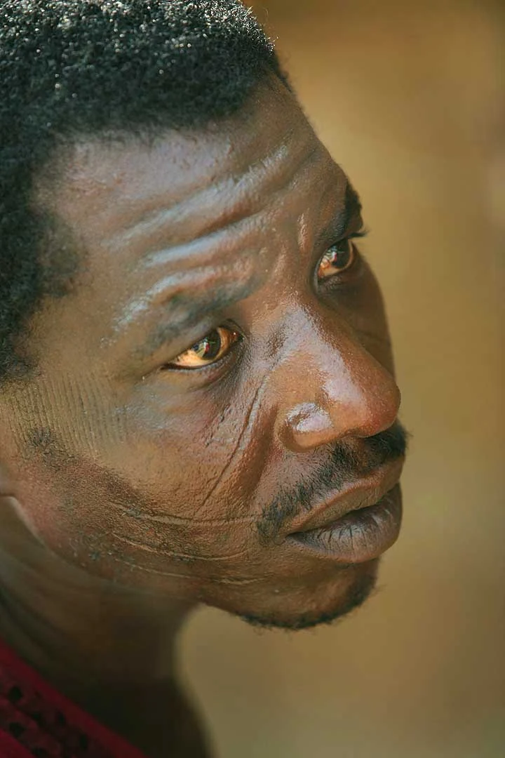 Portrait photographié à Bassam en 2008, montrant des marques sur les joues. La personne n’est pas nommée dans la source.
