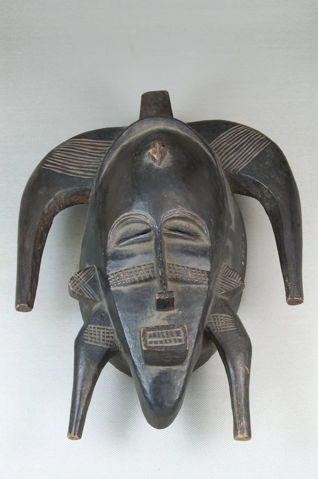 Masque kpeliye’e sénoufo : des marques sculptées quadrillent les joues et le front.
